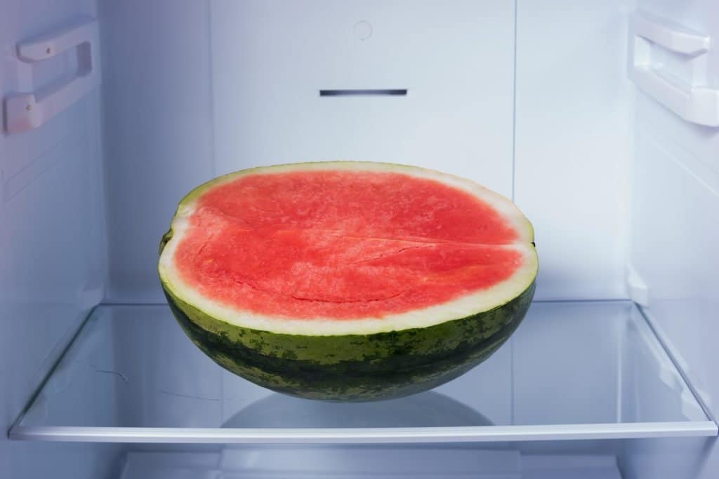 Half of a red watermelon sitting in a refridgerator