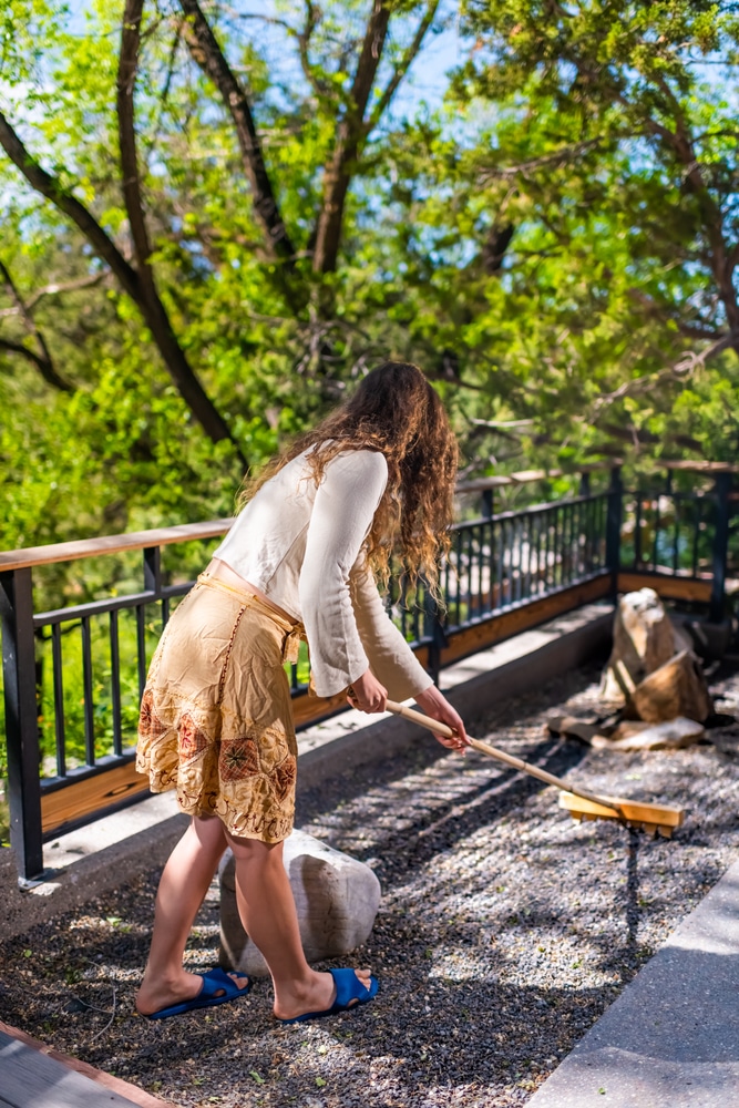 A woman is peacefully raking a zen garden to reduce stress