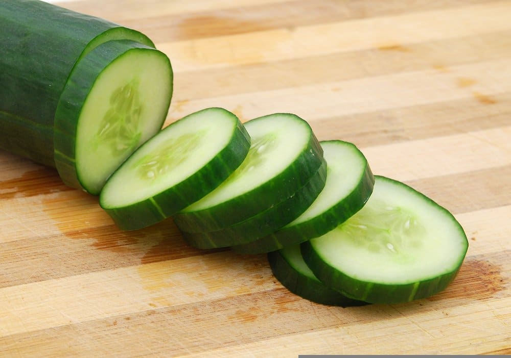 A slicing cucumber that is sitting on a cutting board